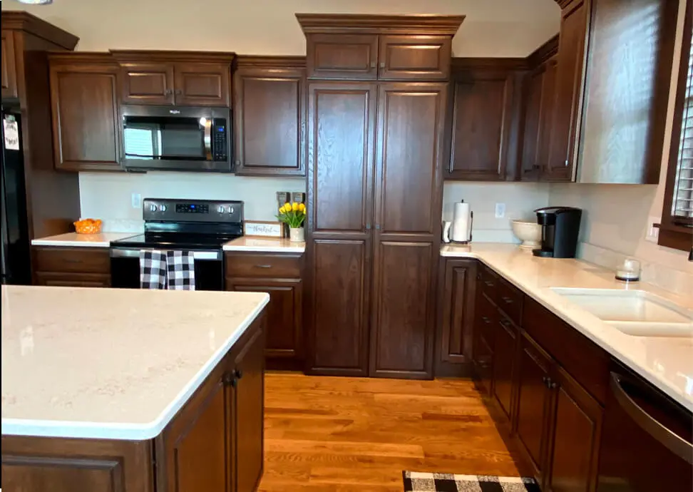 A kitchen with brown cabinets and white counters.